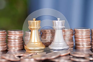 Stacks of dollar coins in front of the two chess pieces in a duel