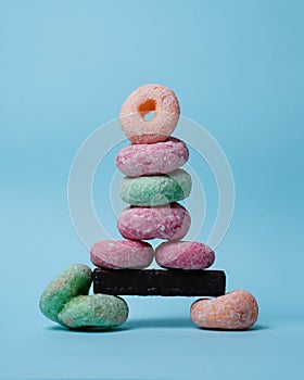 Stacks of donuts of various colors with a topping of powdered sugar form a tower.