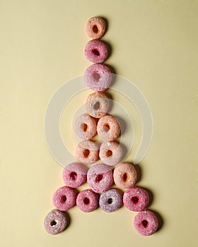 Stacks of donuts of various colors with a topping of powdered sugar form a tower.