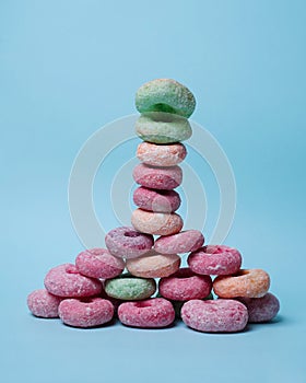 Stacks of donuts of various colors with a topping of powdered sugar form a tower.