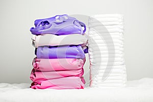 Stacks of eco friendly washable textile diapers and modern disposable diapers together.