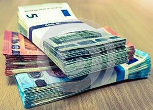 Stacks of Euro bills on a pine desk in fives, tens and twenties photo