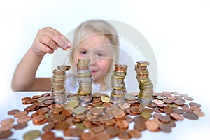 Stacks of euro currency coins, small child, blonde girl 3 years old playing with cash, pocket money against white background,