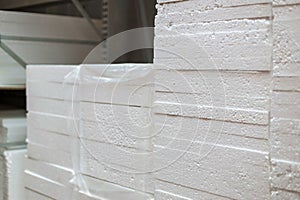 Stacks of expanded polystyrene in packaging at a building materials warehouse in a store. The insulation lies on metal racks in