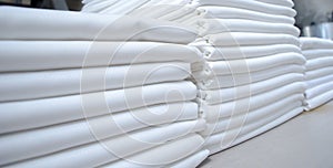 Stacks of folded white fabrics or sheets in an industrial laundry photo