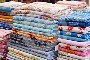 stacks of handmade patchwork quilts at a stall