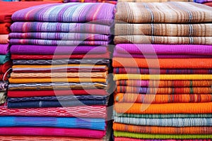 stacks of handwoven rugs in vibrant colors