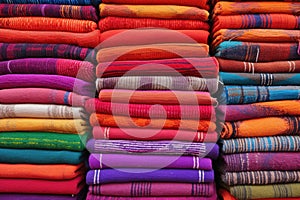 stacks of handwoven rugs in vibrant colors