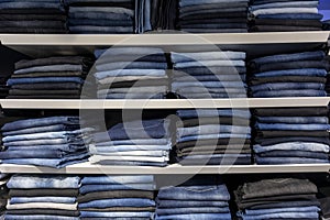 Stacks of jeans on shelves in a fashion store. jeans clothes on shelf in shop.