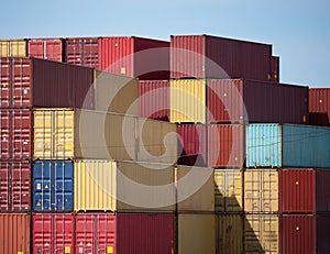 Stacks of large iron cargo containers for transporting import and export of various goods by sea vessels in industrial