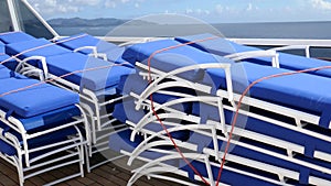 Stacks of lounge chairs on cruise ship deck with ocean in background