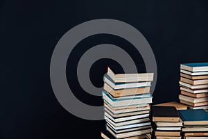 Stacks of old educational books in library on black background