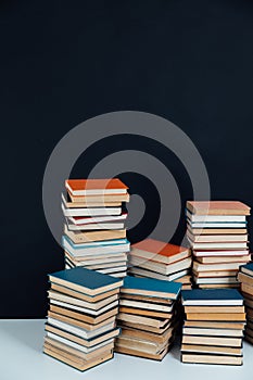 Stacks of old educational books in library on black background
