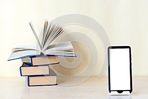 Stacks of old paper books back in the foreground modern digital gadgets: tablet, phone