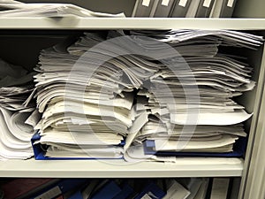 Stacks of paperwork in overflowing cupboard photo