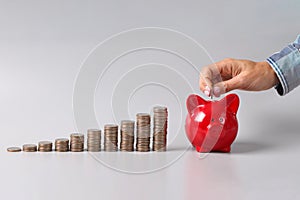 Stacks of rising financial coins and piggy bank person throws coin