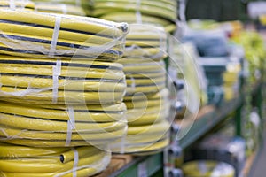 stacks of rolls yellow pvc plastic pipe on the counter in the store. Sale Hoses in the garden of various manufacturers, on shelves