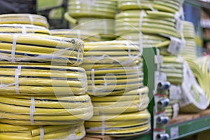 stacks of rolls yellow pvc plastic pipe on the counter in the store. Sale Hoses in the garden of various manufacturers, on shelves