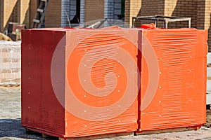 Stacks of silicate bricks on wooden pallets and in polyethylene