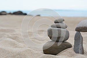 Stacks of stones on beautiful sandy beach near sea, space for text