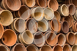 Stacks of terracotta flowerpots in a gardeners potting shed at botanical garden. Many stacked ceramic pots for plants. Old ceramic