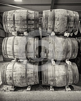 Stacks of traditional full whisky barrels, set down to mature, in a large warehouse