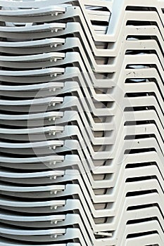 Stacks of white plastic chaise-lounge beach beds