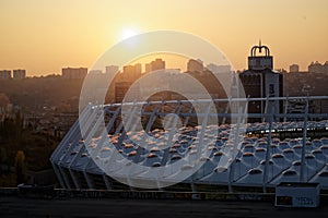 Stadium construction. Aerial view of the stadium roof on the city`s background. Sunset behind stadium for soccer