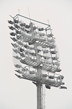 Stadium floodlight with metal pole, lighting mast, tower with floodlights in the sports stadium against the white sky