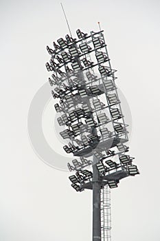 Stadium floodlight with metal pole, lighting mast, tower with floodlights in the sports stadium against the white sky