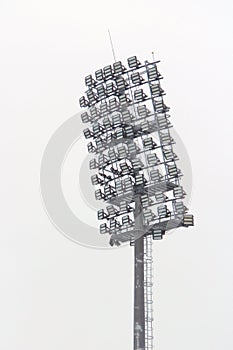 Stadium floodlight with metal pole, lighting mast, tower with floodlights in the sports stadium against the white sky