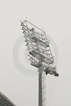 Stadium floodlight with metal pole, lighting mast, tower with floodlights in the sports stadium against the white sky