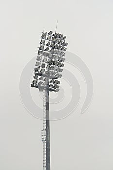 Stadium floodlight with metal pole, lighting mast, tower with floodlights in the sports stadium against the white sky