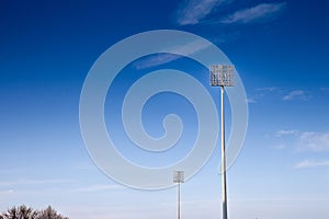Stadium floodlights, used to lit a sports arena, also called reflectors or projectors, during a sunny afternoon. These are high