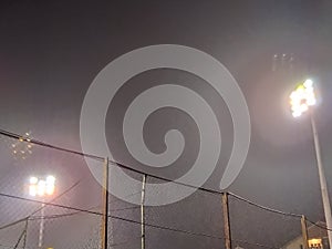 Stadium in lights and flashes. Empty beautiful football field with glowing spotlights in the evening or at night. Fog or smoke