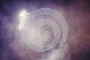 Stadium lights and smoke against dark night sky background