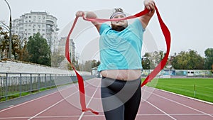 At the stadium obese guy running fast to the finish line to win the marathon he wants to loose the weight he have a