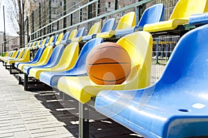 Stadium seats and basketball ball on it.Empty seats for fans at the sport court