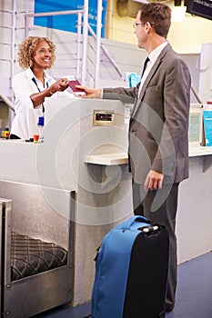 Staff At Airport Check In Desk Handing Ticket To Businessman