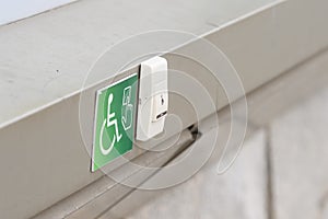 A staff call button for people with reduced mobility on a green sign