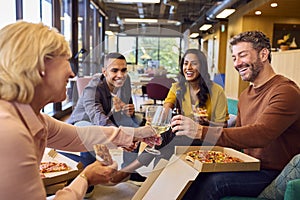 Staff At Informal Meeting In Office With Takeaway Pizza And Drinks