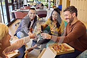 Staff At Informal Meeting In Office With Takeaway Pizza And Drinks