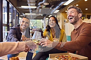 Staff At Informal Meeting In Office With Takeaway Pizza And Drinks