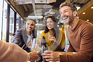 Staff At Informal Meeting In Office With Takeaway Pizza And Drinks