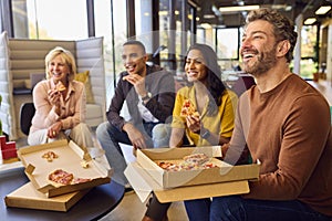 Staff At Informal Meeting In Office With Takeaway Pizza And Drinks