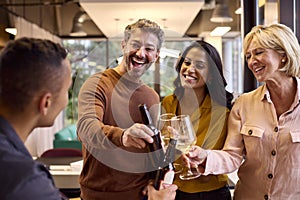 Staff At Informal Team Meeting In Office Celebrating With Drinks