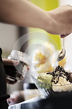 Staff making italian gelato ice cream sundae in modern shop