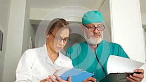 Staff of the medical clinic. Close portrait of two doctors, a mature man and a young woman. Doctors look at the camera