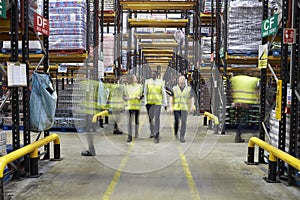 Staff in reflective vests walking to camera in a warehouse