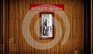 Staff Only Sign on a Wooden Door with a Small WIndow.